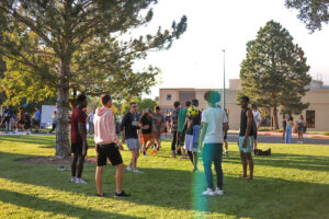 A group of young men in a circle kicking a soccer ball amongst themselves outside on the lawn.